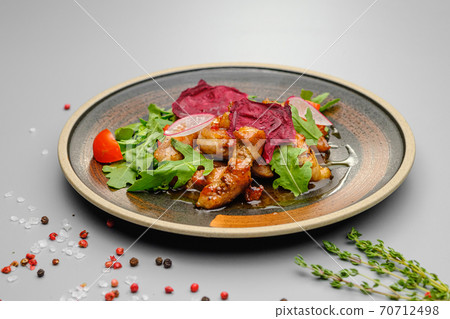 Grilled grilled meat in sauce with vegetables on a white plate. 70712498