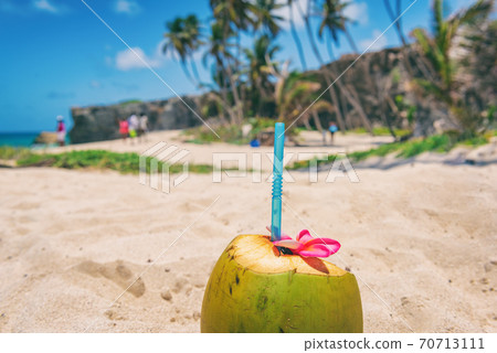 Fresh coconut water drink on beach resort holiday background with reusable eco-friendly plastic straw natural healthy food. Tropical vacation. Bottom Bay beach, Barbados, Caribbean travel 70713111