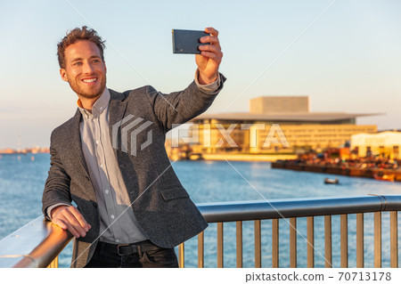 Selfie business man professional young businessman taking photo with phone or vlogging live stream video recording on videoconference using cellphone. Europe travel lifestyle Selfie business man professional young businessman taking photo with phone or vlogging live stream video recording on videoconference using cellphone. Europe travel lifestyle 70713178