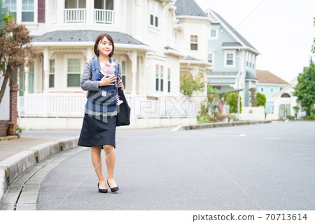 Working mother on the way to work holding a baby 70713614