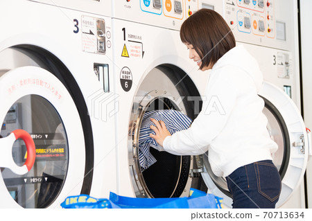 洗滌在硬幣洗衣店的少婦 洗滌在硬幣洗衣店的少婦 70713634