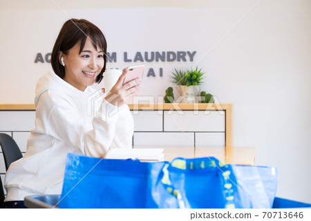 Woman waiting at a laundromat cafe 70713646