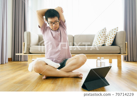 New normal Training At Home An Asian man, aged 35-40, with brown skin, Home exercise. exercising in living room. 70714229