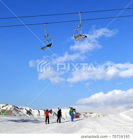 Three skiers on slope at sun winter day 70716195