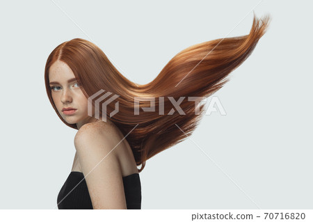 Beautiful model with long smooth, flying red hair isolated on white studio background. 70716820