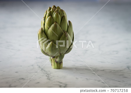 A green fresh artichoke on a marble counter 70717258