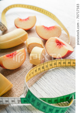 Slices of banana and peach spread out on a sack on a black wooden table with a centimeter. Diet breakfast and body control Slices of banana and peach spread out on a sack on a black wooden table with a centimeter. Diet breakfast and body control 70717383