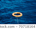 An Orange Lifebuoy Floating in the Middle of the Ocean 70718164