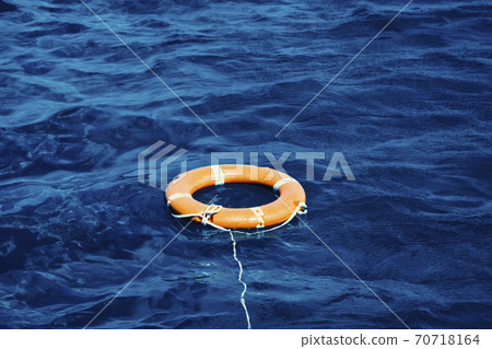 An Orange Lifebuoy Floating in the Middle of the Ocean 70718164
