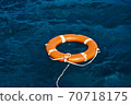 An Orange Lifebuoy Floating in the Middle of the Ocean 70718175