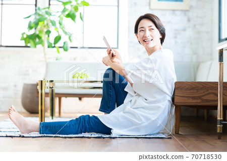 Middle-aged woman operating a smartphone in the living room 70718530