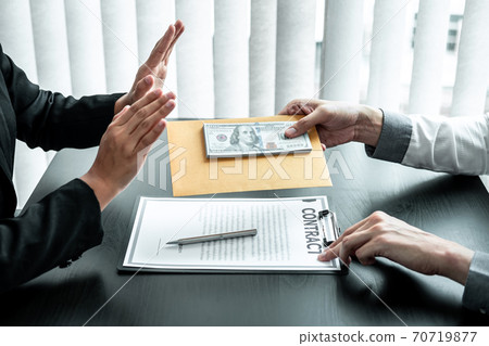 Business woman refusing receive bribe money in the envelope of their partner to give success the deal contract in a corruption scam, illegal and dishonest 70719877