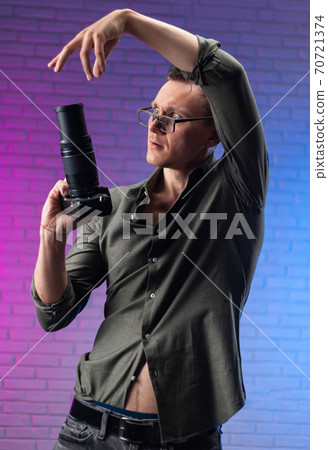 crazy man in glasses with a digital camera on a bright neon background 70721374