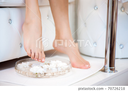 Female feet with spa bowl, towel and flowers on white background Female feet with spa bowl, towel and flowers on white background 70726218