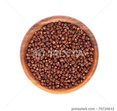 Guinea pepper grains in wooden bowl, isolated on white background. Melegeta, alligator pepper or mahlab. Grains of paradise. Top view. 70726632