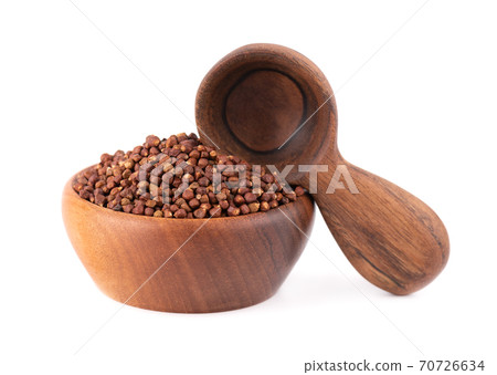 Guinea pepper grains in wooden bowl and spoon, isolated on white background. Melegeta, alligator pepper or mahlab. Grains of paradise. 70726634