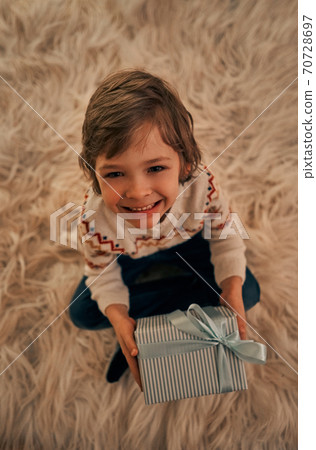 The cute boy with a gift box sitting on the floor The cute boy with a gift box sitting on the floor 70728697