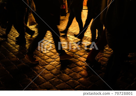 The feet of people walking on the cobblestones on a night after the rain The feet of people walking on the cobblestones on a night after the rain 70728801