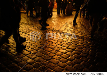 The feet of people walking on the cobblestones on a night after the rain 70728802