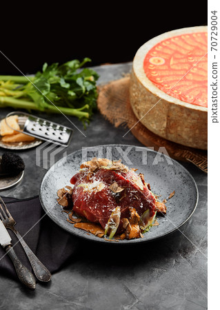 A plate of salad with beef roast beef, onions, arugula, pepper and tomatoes on a black table. Top view. A plate of salad with beef roast beef, onions, arugula, pepper and tomatoes on a black table. Top view. 70729004