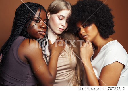 young pretty caucasian, afro, scandinavian woman posing cheerful together on brown background, lifestyle diverse nationality people concept young pretty caucasian, afro, scandinavian woman posing cheerful together on brown background, lifestyle diverse nationality people concept 70729242