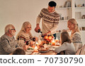 The happy man fills wine glasses above the festive table 70730790