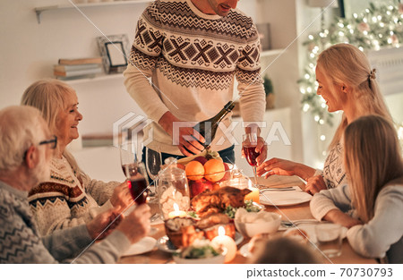 The man fills wine glasses above the festive table The man fills wine glasses above the festive table 70730793