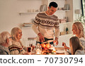 The happy man fills wine glasses above the festive table 70730794