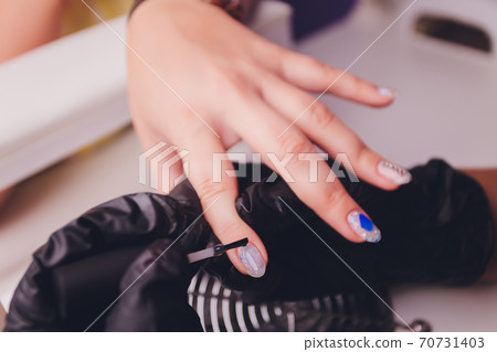 woman doing manicure in a beauty salon. Close-up of hands. 70731403