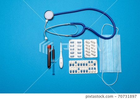 prevention and treatment of coronavirus healthcare concept - syringe, mask, tablets, stethoscope and Covid-19 test tube on blue background 70731897