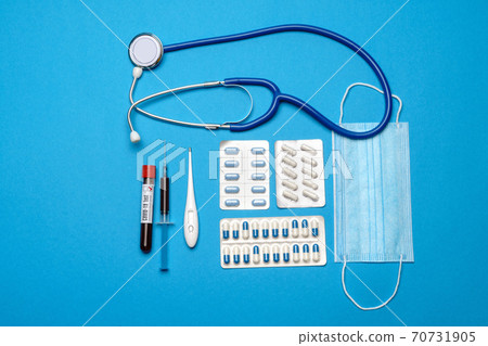 prevention and treatment of coronavirus healthcare concept - syringe, mask, tablets, stethoscope and Covid-19 test tube on blue background prevention and treatment of coronavirus healthcare concept - syringe, mask, tablets, stethoscope and Covid-19 test tube on blue background 70731905