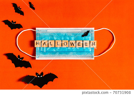 lettering Halloween on a medical protective mask on a black background with silhouettes of bats made 70731908