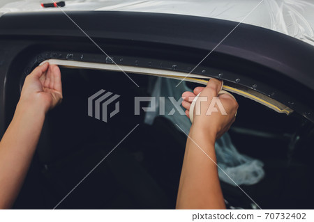 Mechanic preparing a car for painting by protecting the edges. Mechanic preparing a car for painting by protecting the edges. 70732402