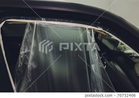 Mechanic preparing a car for painting by protecting the edges. Mechanic preparing a car for painting by protecting the edges. 70732406