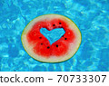 A heart shaped watermelon, floating in the blue waters of the Mediterranean Sea.  70733307