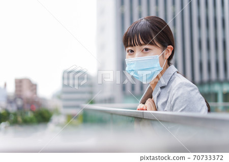 Young business woman walking in the business district wearing a mask Young business woman walking in the business district wearing a mask 70733372