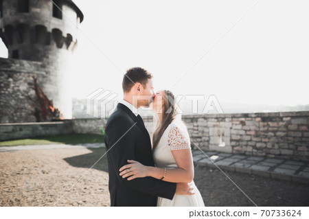 Beautiful romantic wedding couple of newlyweds hugging near old castle Beautiful romantic wedding couple of newlyweds hugging near old castle 70733624