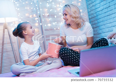 Grandmother and granddaughter eat popcorn. Grandmother and granddaughter eat popcorn. 70735532