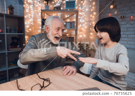 Grandfather and grandson play games at home. 70735625