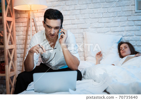 A man in a shirt works late into the night. A man in a shirt works late into the night. 70735640