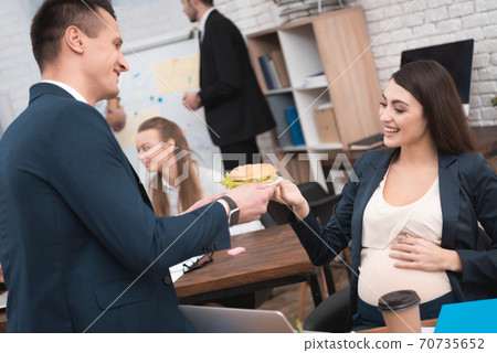 A man gives his sandwich to a pregnant woman. 70735652