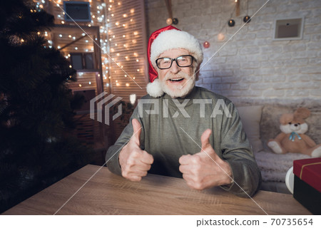 Grandfather is sitting near Cristmas tree. Grandfather is sitting near Cristmas tree. 70735654