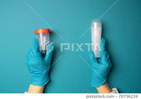 Doctor hands in latex rubber gloves holding a plastic container and a lubricant of liquids on blue background Doctor hands in latex rubber gloves holding a plastic container and a lubricant of liquids on blue background 70736239