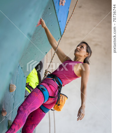 Young woman climber resting on the climbing wall 70736744