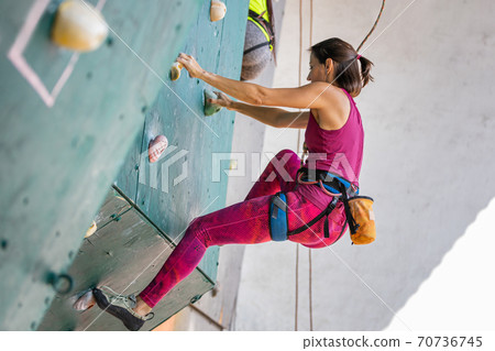 Young woman climber on the climbing wall Young woman climber on the climbing wall 70736745