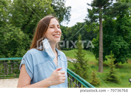 Young woman feels happy and breathes fully after put off medical mask 70736768