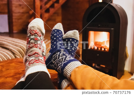 Feet in wool socks warming near fireplace in rustic cabin house. Cozy winter. 70737176