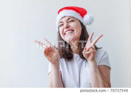 Beautiful girl in red Santa Claus hat isolated on white background. Winter portrait of young woman. Happy Christmas and New Year holidays concept. Beautiful girl in red Santa Claus hat isolated on white background. Winter portrait of young woman. Happy Christmas and New Year holidays concept. 70737549