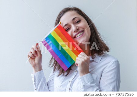 Beautiful caucasian lesbian girl with LGBT rainbow flag isolated on white background looking happy and excited. Young woman Gay Pride portrait. Equal rights for lgbtq community concept. Beautiful caucasian lesbian girl with LGBT rainbow flag isolated on white background looking happy and excited. Young woman Gay Pride portrait. Equal rights for lgbtq community concept. 70737550