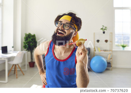 Portrait of a crazy emotional joyful athlete man holding a medal in his hand and flaunting it. Portrait of a crazy emotional joyful athlete man holding a medal in his hand and flaunting it. 70737620